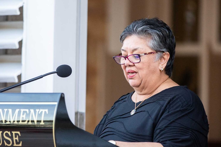 lady reading from a lectern into a microphone at an event