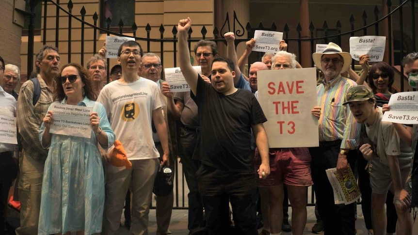 Protestors hold signs outside of NSW Parliament