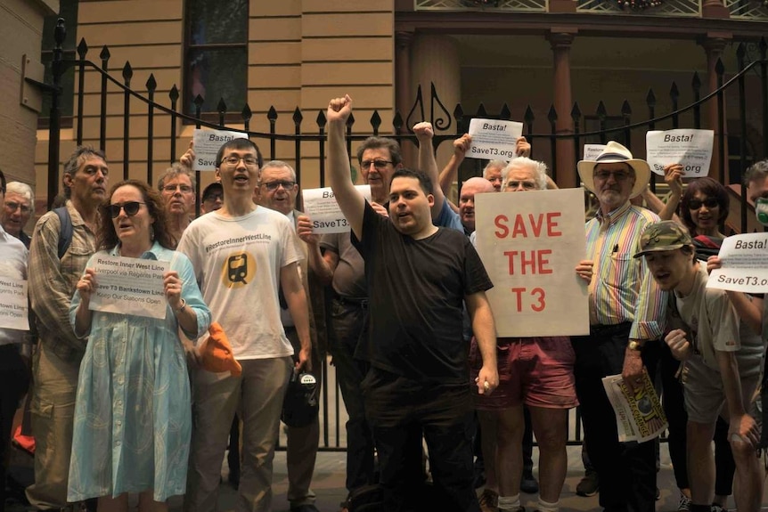 Protestors hold signs outside of NSW Parliament