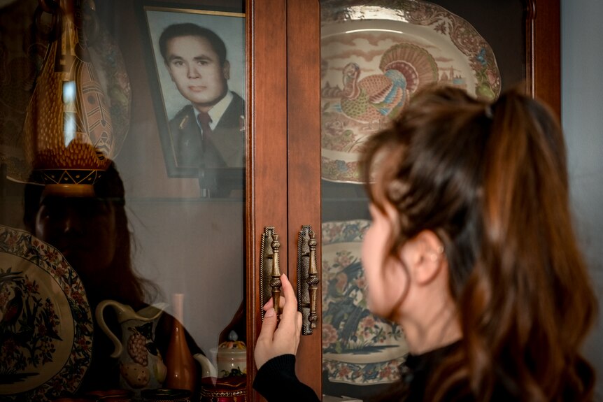 A young woman looks at a photo of a man.