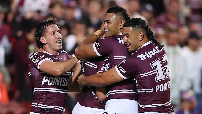 A group of rugby league players celebrate after scoring a try