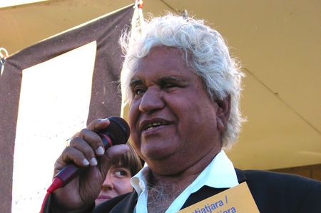 Yami Lester speaking to a crowd and holding an indigenous language book.