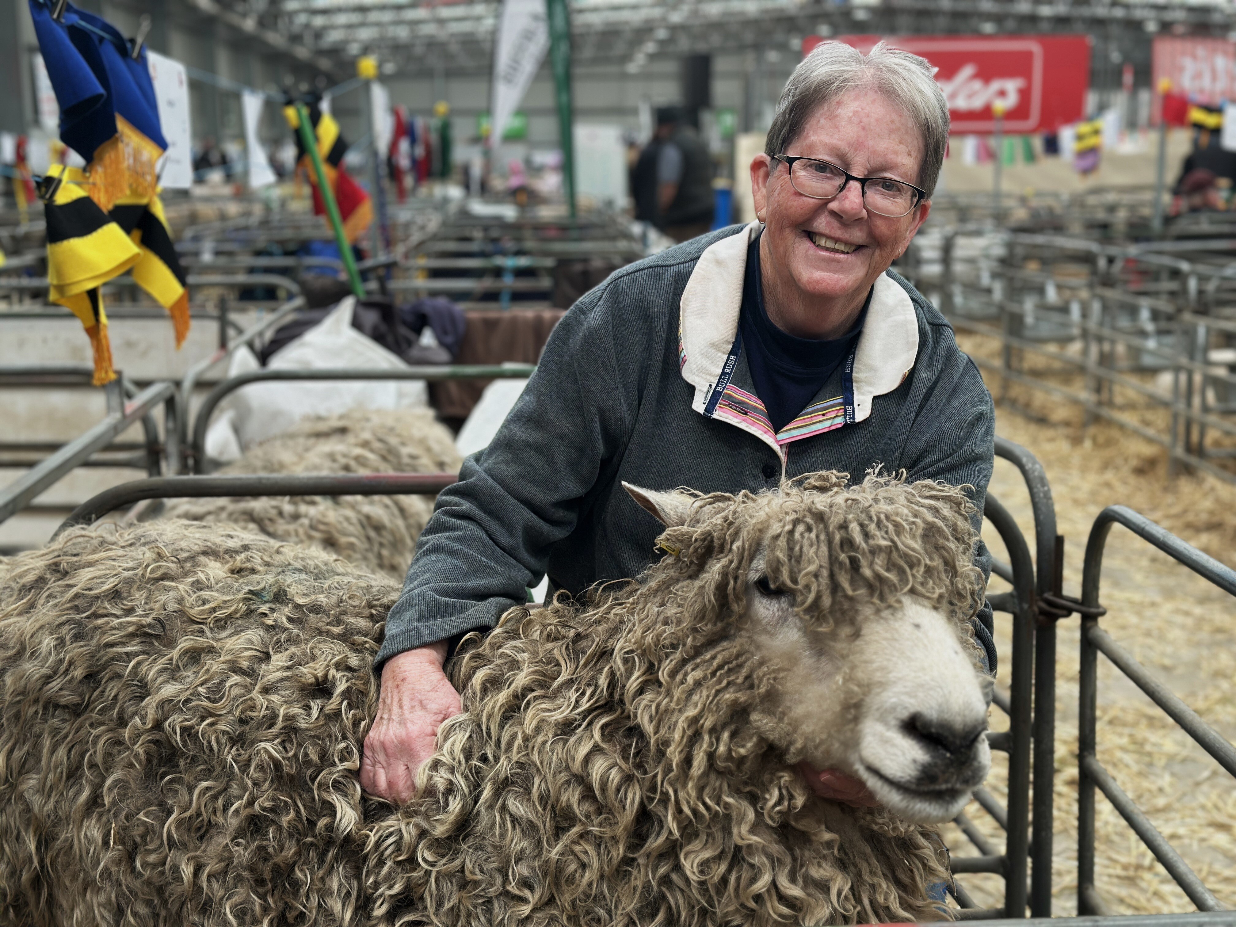 A woman smiles as she holds a sheep.