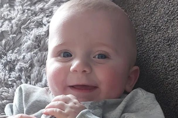 A small baby looks at camera and smiles.