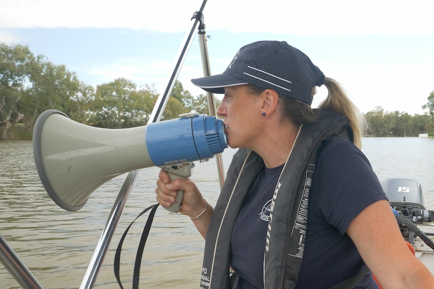 Bec Marshall instructs the Wentworth rowers via megaphone from a boat, Wentworth, NSW, November 2023.