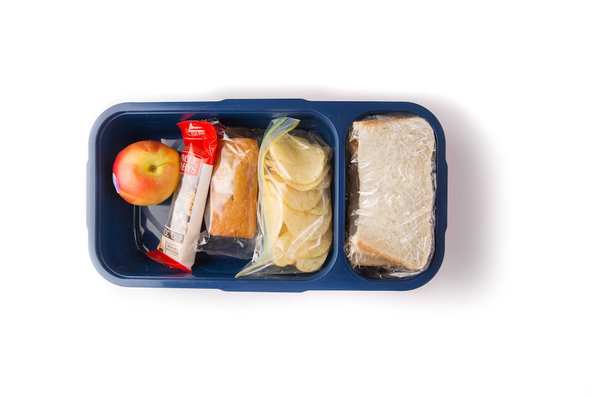 A Nutella sandwich, potato chips, cake, a choc chip muesli bar and a nectarine in a navy blue lunch box.
