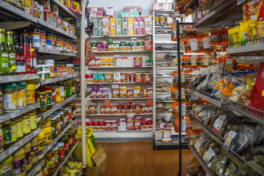 Hundreds of colourfully packaged food items line a grocery aisle.