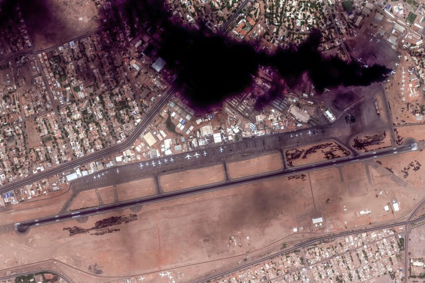 A satellite image of black smoke over a residential area and airport