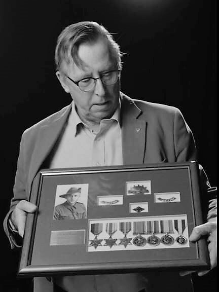 man holding a framed collection of military medals