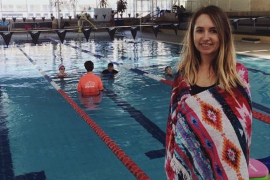 Lauren Roberts stands by a pool wrapped in a towel