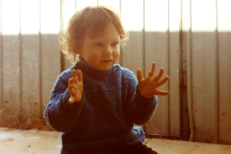 A family photo of a small child sitting on the floor clapping