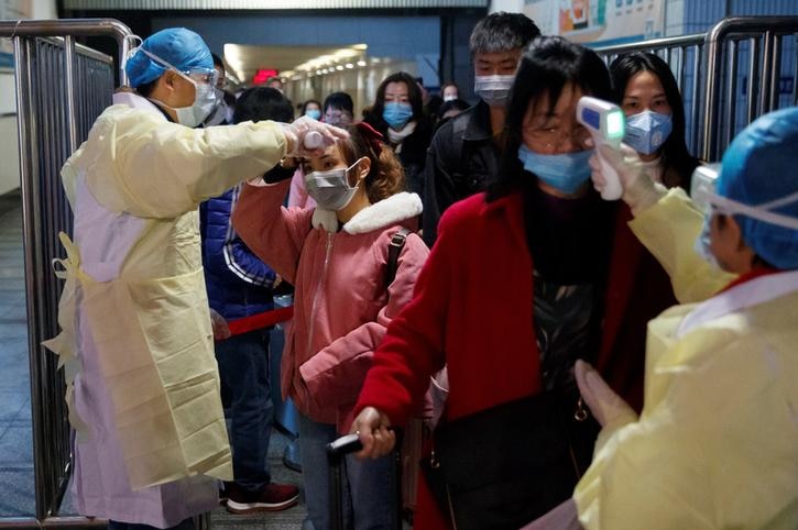 Health workers hold laser thermometers to people's foreheads