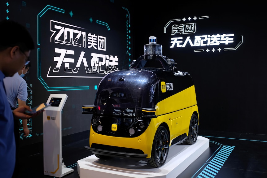 a yellow and black autonomous delivery vehicle displayed on a stand at the World Artificial Intelligence Conference
