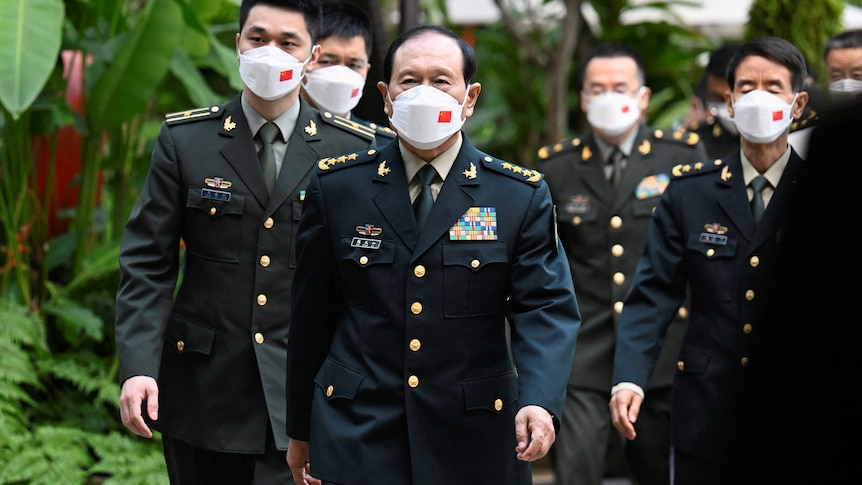 Wei Fenghe and other members of the Chinese delegation walk in military uniform and face masks.