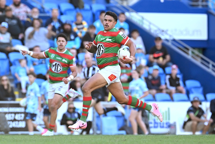 NRL player Latrell Mitchell running with the ball in open space, about to score