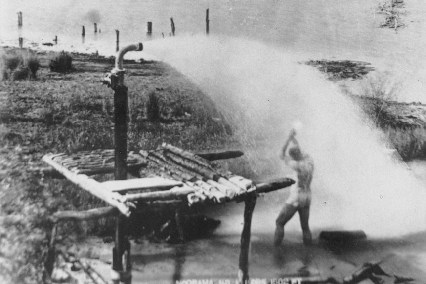 A naked man bathing under a spout of water from a bore in Cunnamulla. 