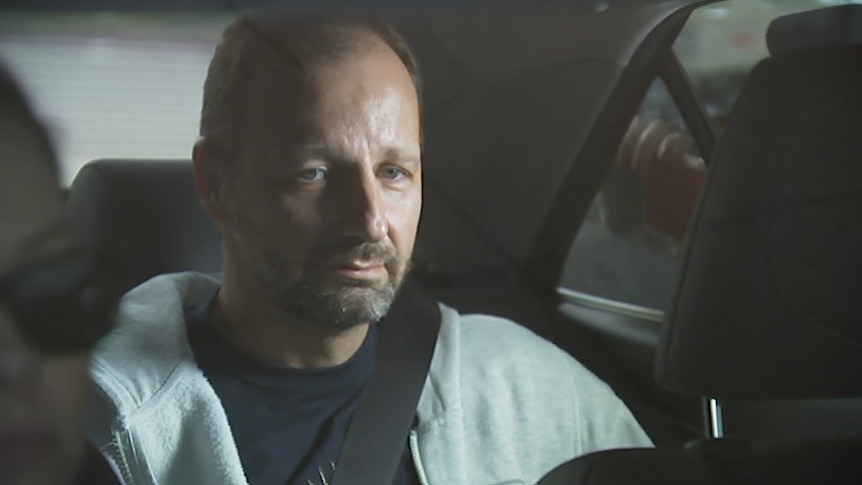 Mr Waden in the back of a police car after being arrested for murder.