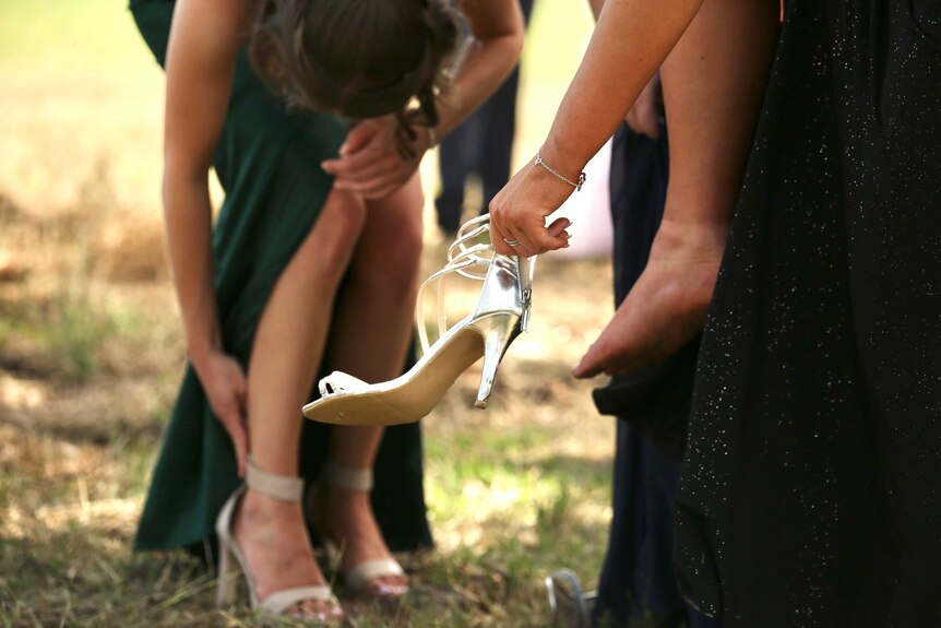 a close up image of a woman putting on a shoe in a paddock