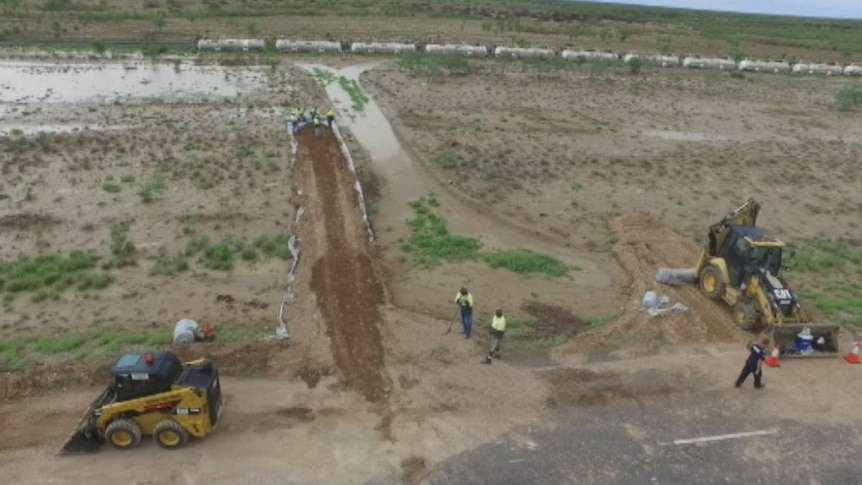 Workers and excavating equipment at site of freight train derailment near Julia Creek