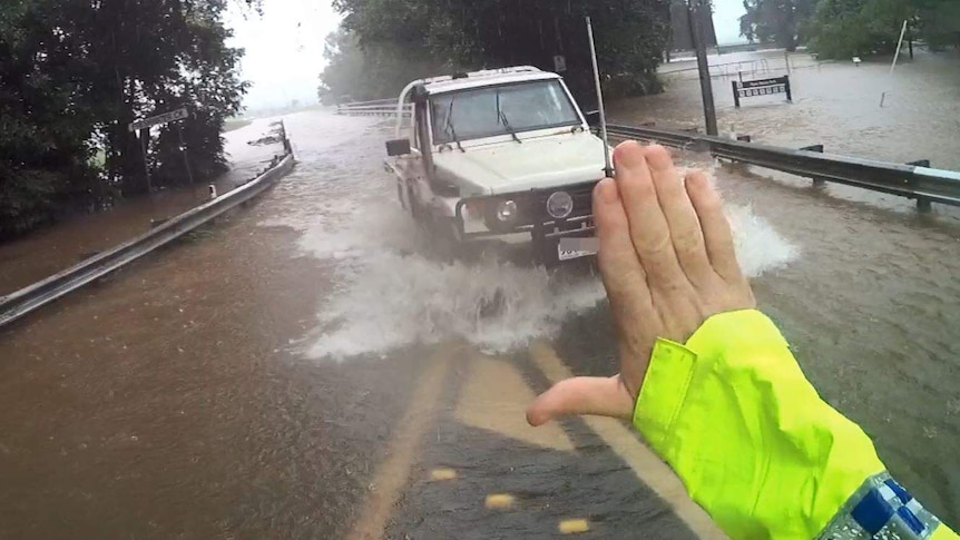 A police officer pulls over a motorist for driving through floodwaters.