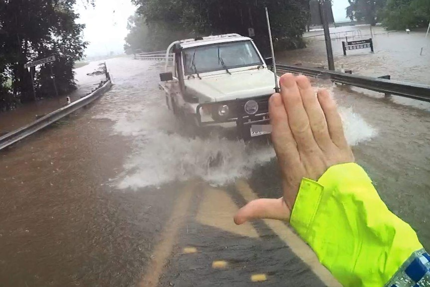 A police officer pulls over a motorist for driving through floodwaters.
