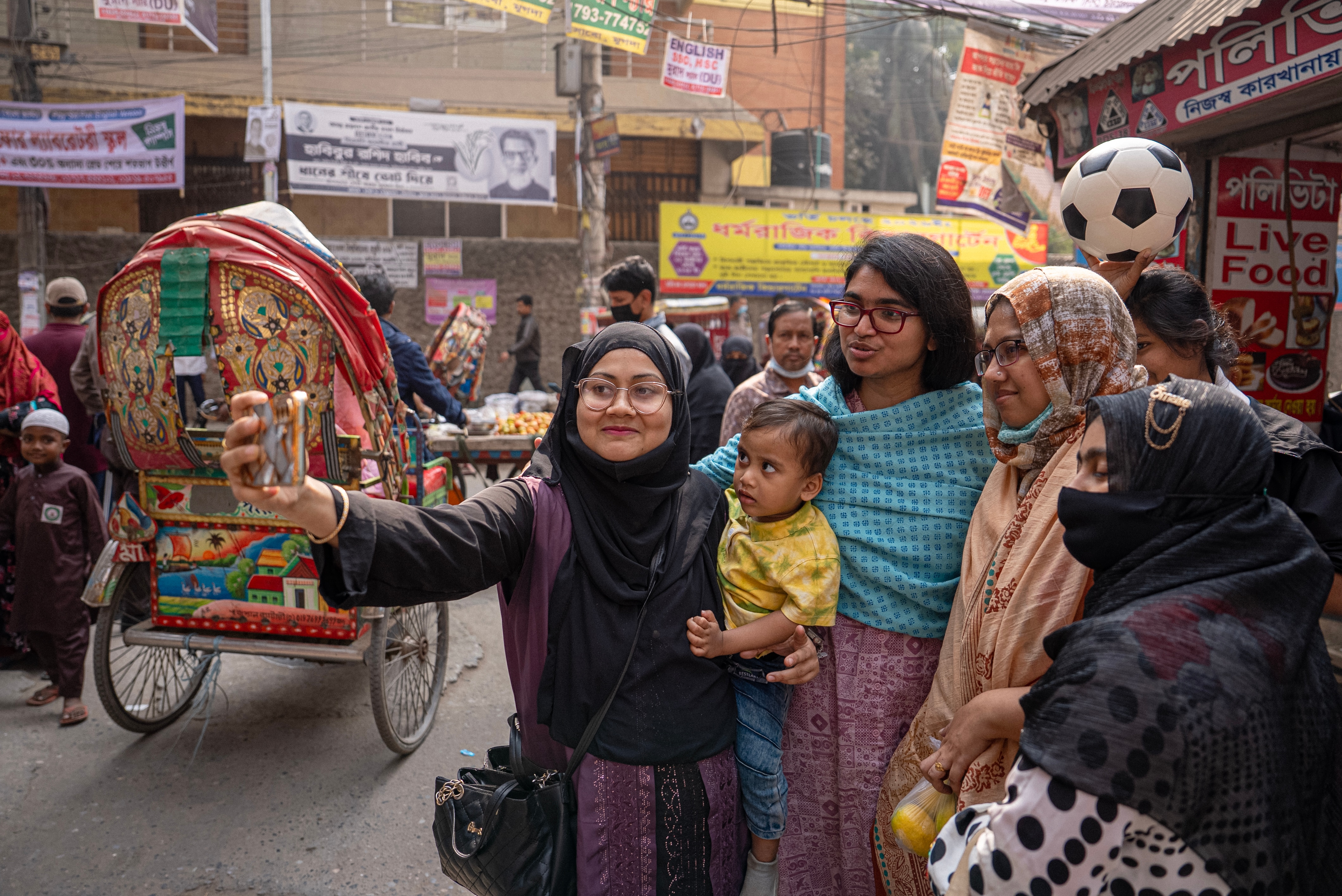 A woman takes a selfie with her family on a street in Bangladesh.