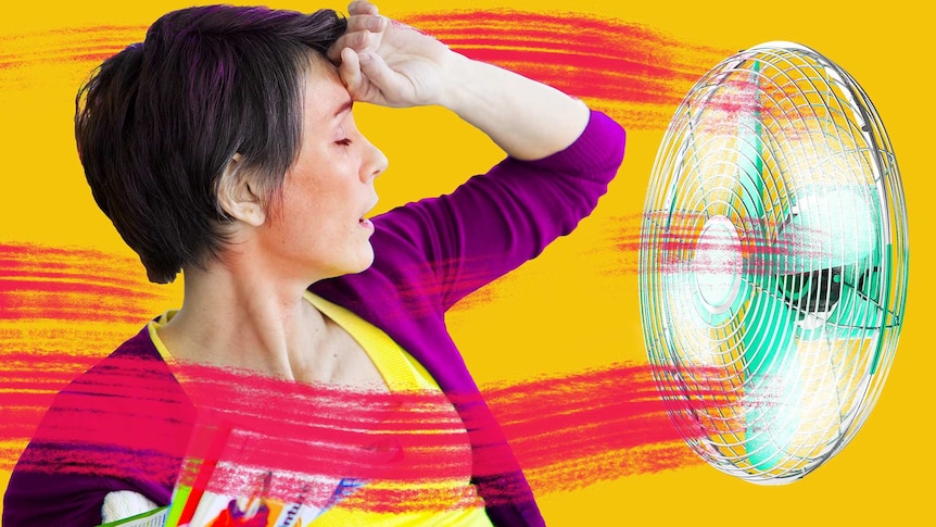 A woman holds her hand to her forehead during a hot flush while a fan blows air attempting to cool her down.