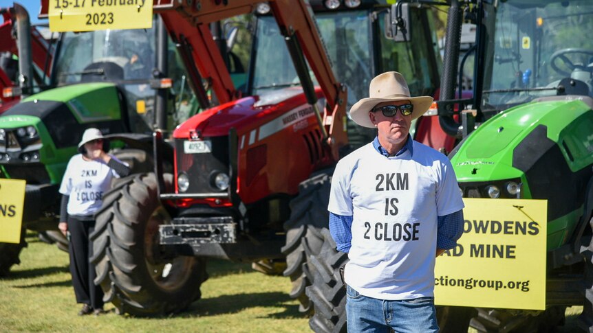 Man standing in front of protest signs and tractors