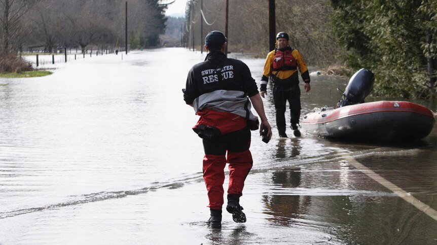 Rescue workers make their way through flood waters after Seattle mudslide