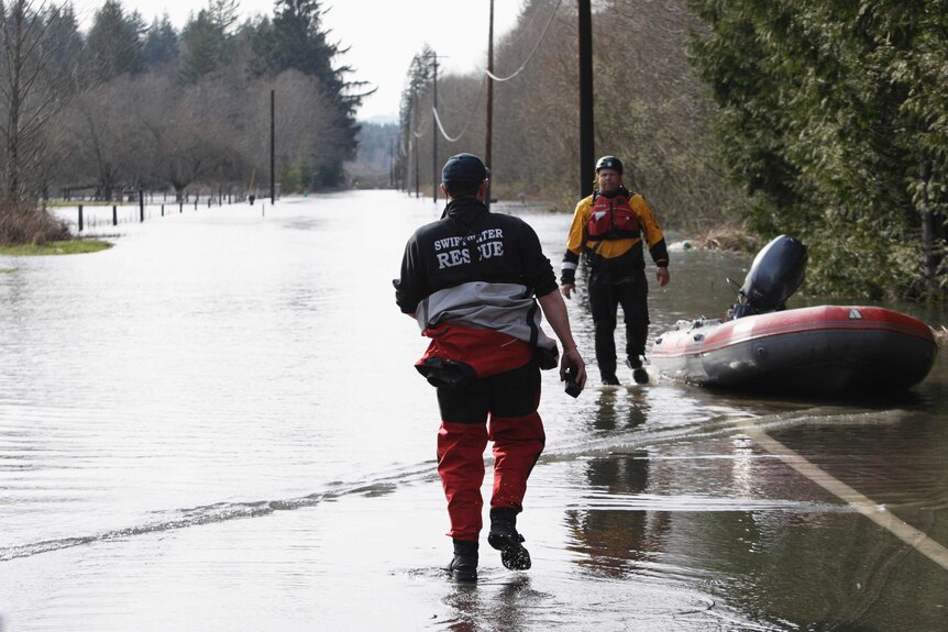 Rescue workers make their way through flood waters after Seattle mudslide