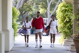 An African American man flanked by two teenage African American girls, wearing tennis outfits, look determined as they walk