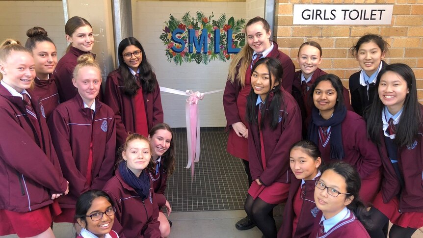 Female students stand near the entrance to their newly decorated toilet block.