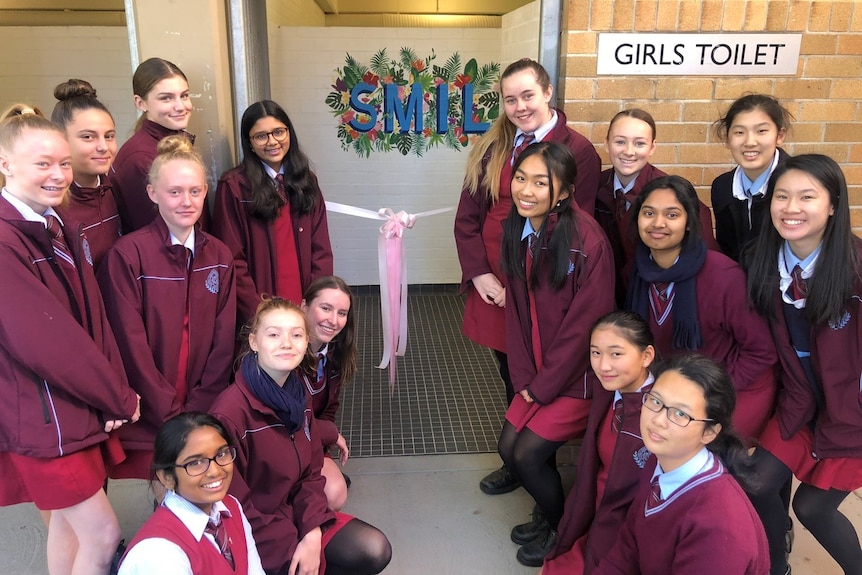 Female students stand near the entrance to their newly decorated toilet block.