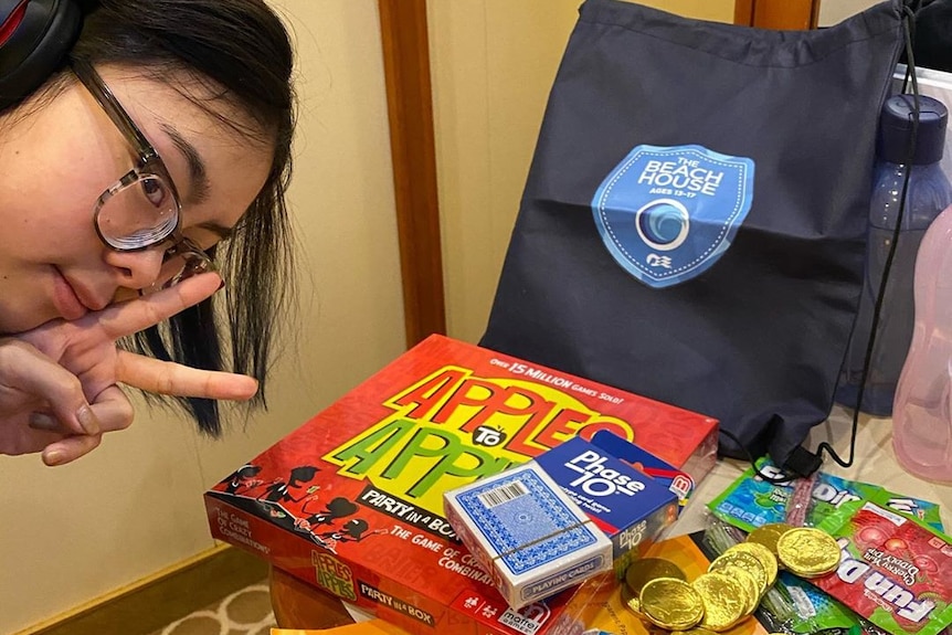 A teenage girl poses near board games and cards.