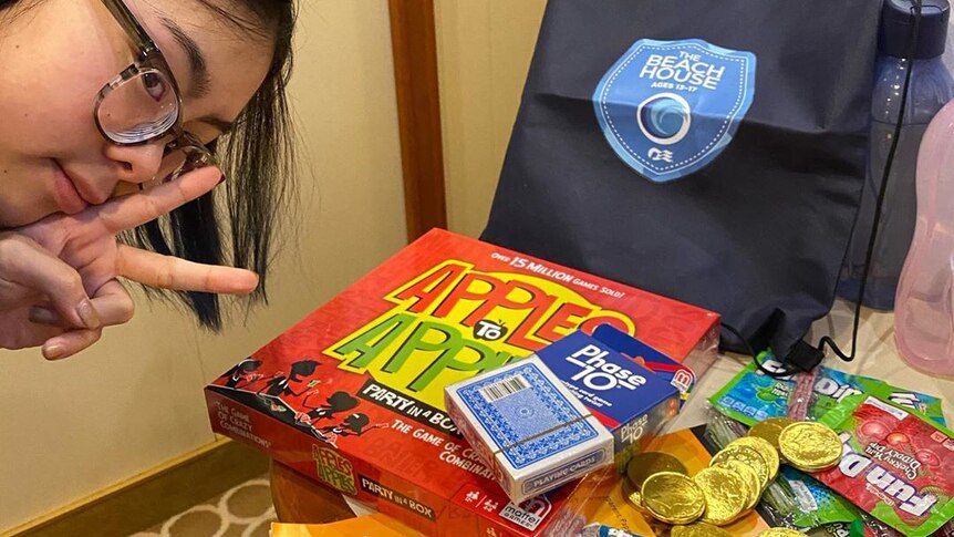 A teenage girl poses near board games and cards.