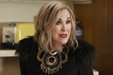 Catherine O'Hara as Moira Rose in Schitt's Creek, dressed in all black with an ornate necklace and jewelled gloves.