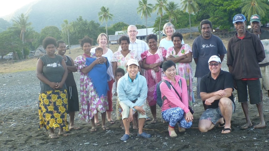 A group of people pose for a photo on a beach.