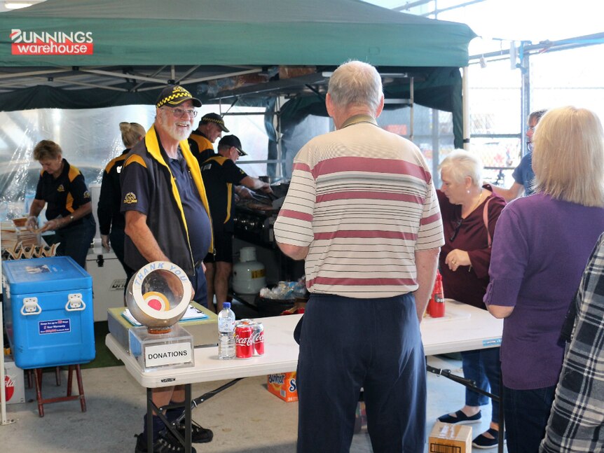 Customers lining up at a charity sausage sizzle.