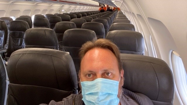 A man wearing a mask in an empty plane.