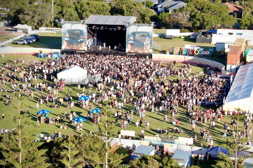 An aerial shot of a people in a crowd in front of a stage