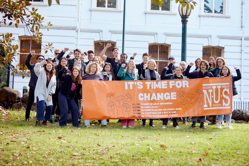 A group of people standing on a lawn holding a banner that reads "It's time for change" 