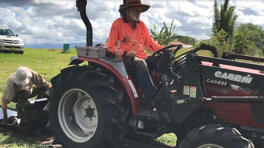 A man on a tractor planting garlic