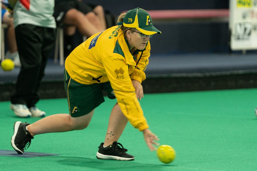 Rebecca Van Asch kneels and bowls.