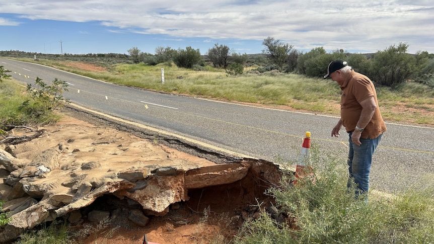 a man standing next to a large hole on a highway