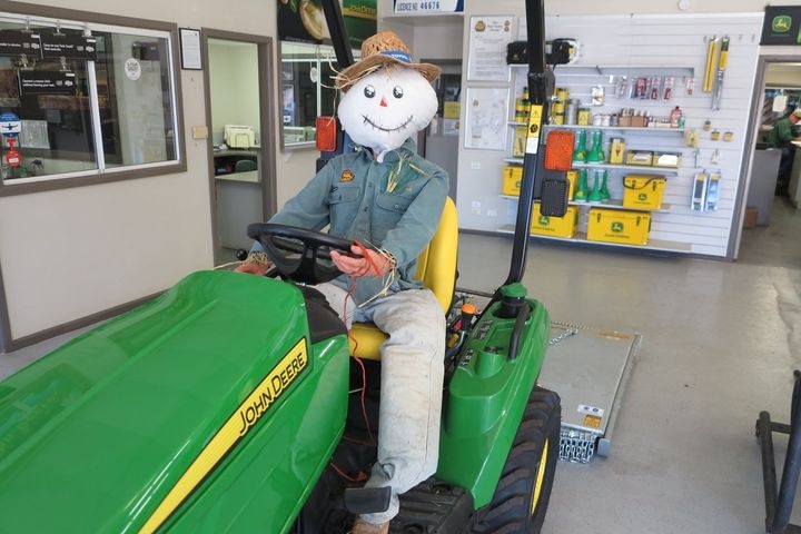 smiling scarecrow driving tractor