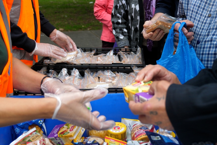 plastic wrapped sandwiches and snacks being given to hands