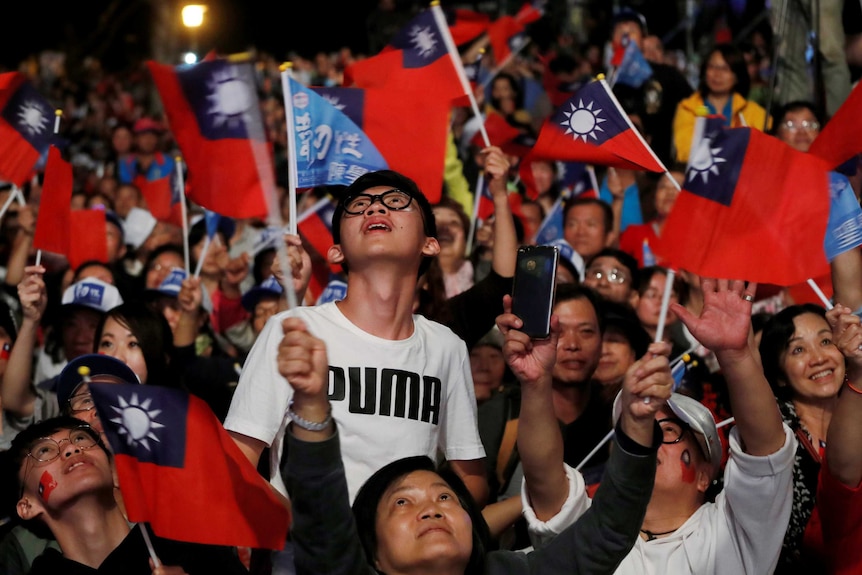 A crowd of people waving Taiwan flags.