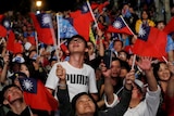 A crowd of people waving Taiwan flags.