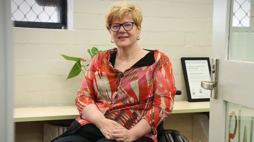 A woman in a wheelchair sits in an office