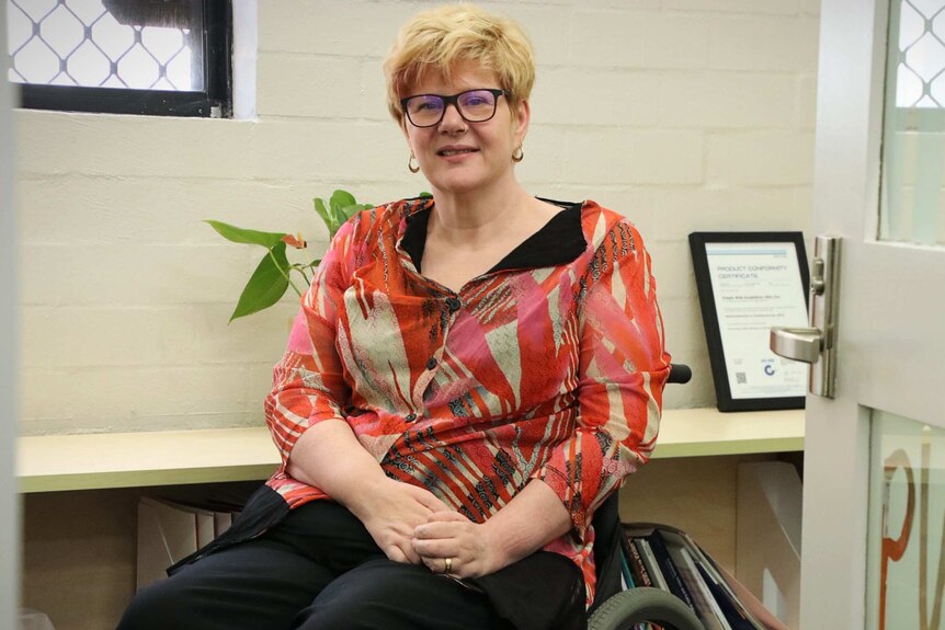 A woman in a wheelchair sits in an office